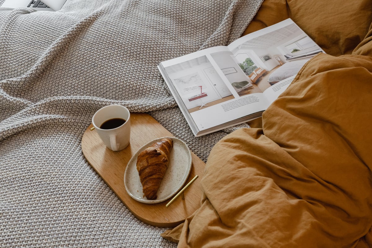 Croissant and Coffee on Wooden Tray with Magazine on Bed